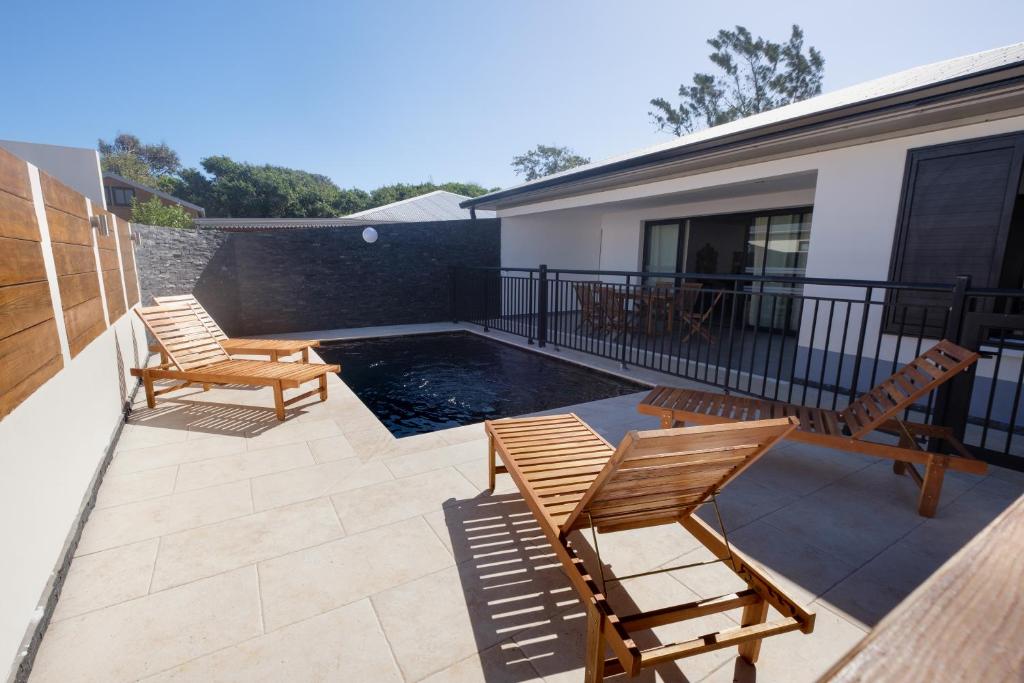 un patio avec deux chaises et une piscine dans l'établissement Villa Cap Noir piscine chauffée avril à octobre, à Saint-Joseph