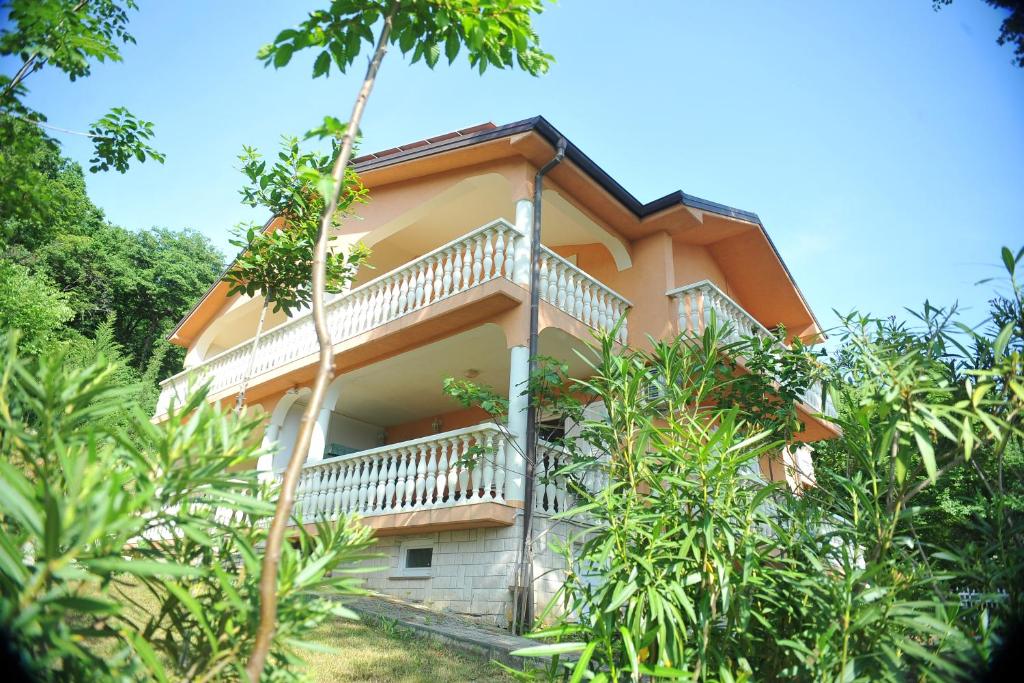 a house with a balcony in the middle of trees at Apartments Viktorija in Omišalj