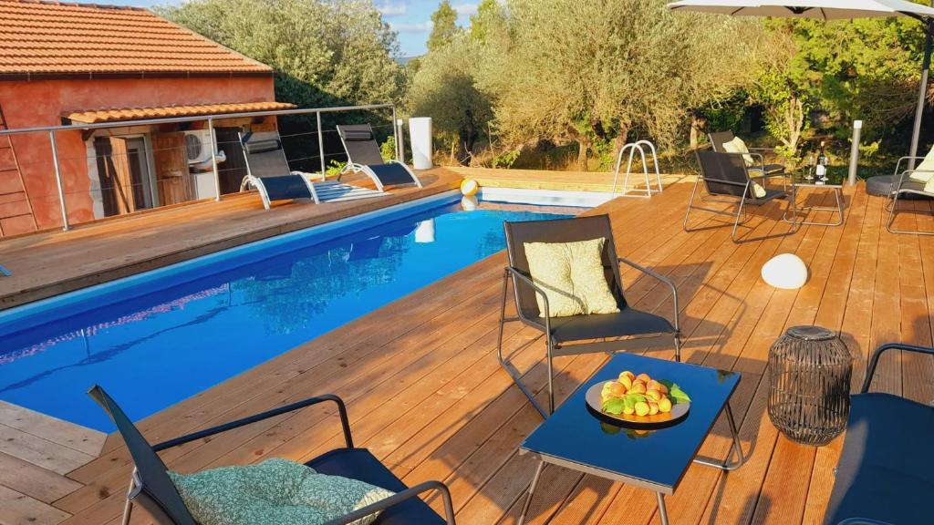 una piscina con sillas y una mesa con un bol de fruta. en Villa Relax tra gli Ulivi, en Alghero