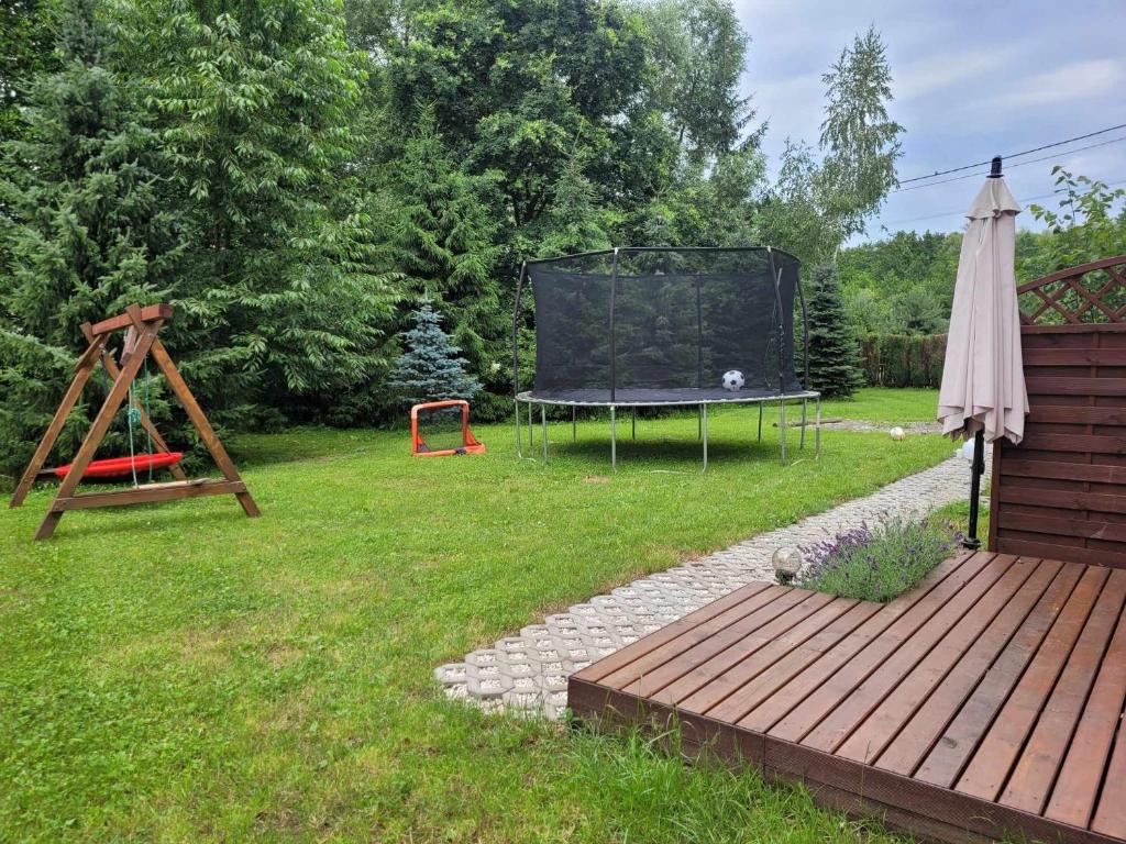 un giardino con tavolo e ombrellone e parco giochi di Apartament na Kasztanowej a Piotrowice