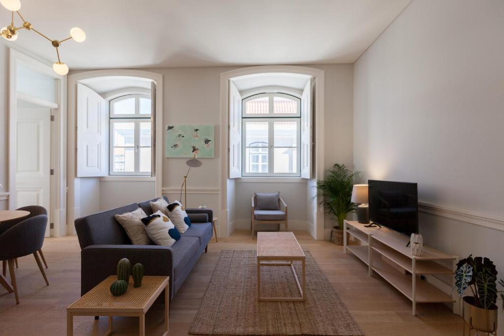 ein Wohnzimmer mit einem blauen Sofa und einem TV in der Unterkunft FLH Praça Rossio Bright Apartment in Lissabon