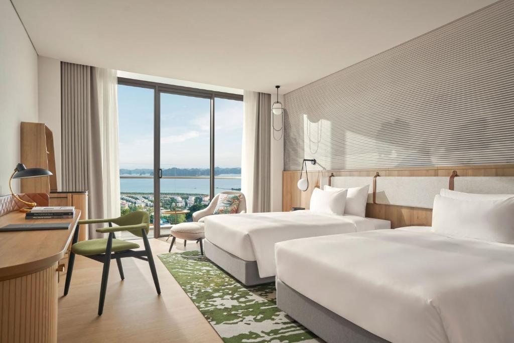 Cette chambre comprend deux lits et un bureau. dans l'établissement The Yacht Hotel by DC, à Hạ Long