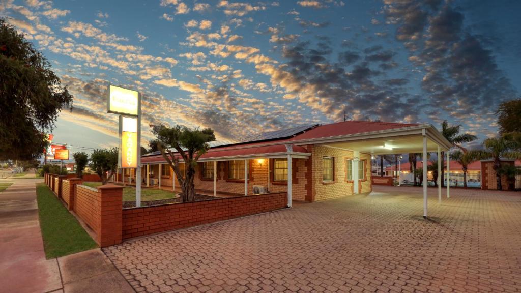 a building with a cloudy sky above it at Charles Rasp Motor Inn & Cottages in Broken Hill