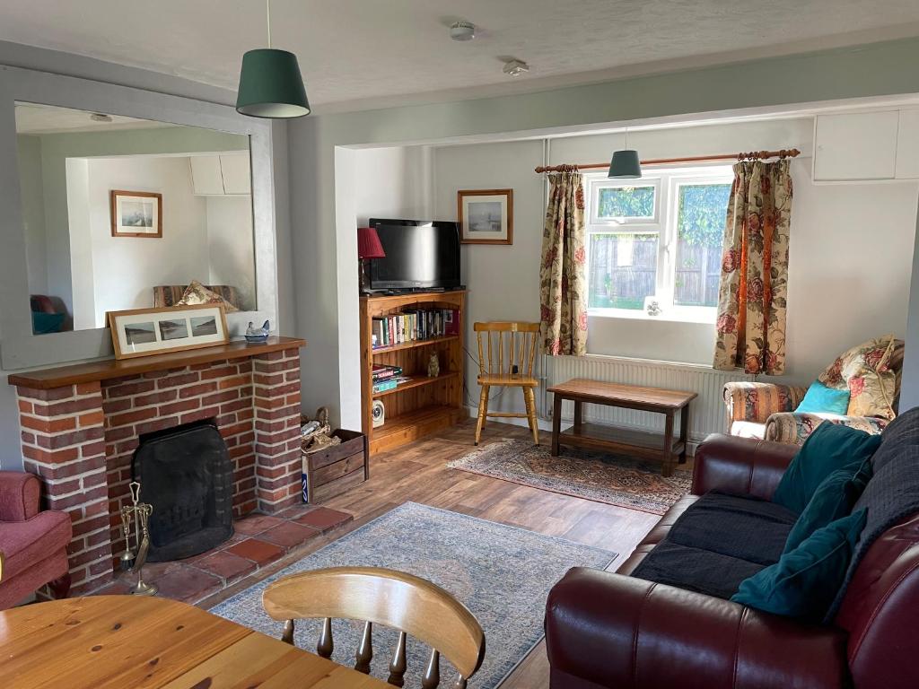 a living room with a couch and a fireplace at Betty's Cottage - Traditional Norfolk Farm Cottage in Swafield