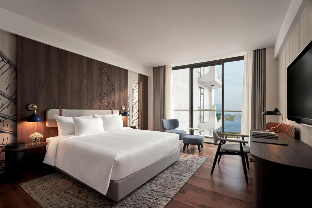 een slaapkamer met een groot wit bed en een bureau bij The Yacht Hotel by DC in Ha Long