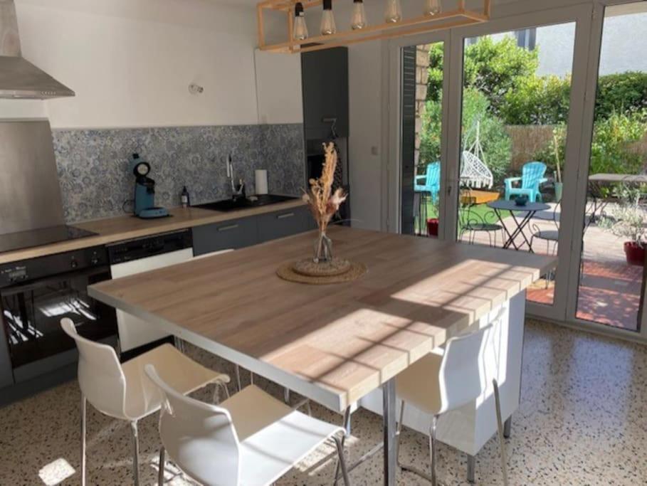 a kitchen with a wooden table and white chairs at Une pause au paradis in Sorgues