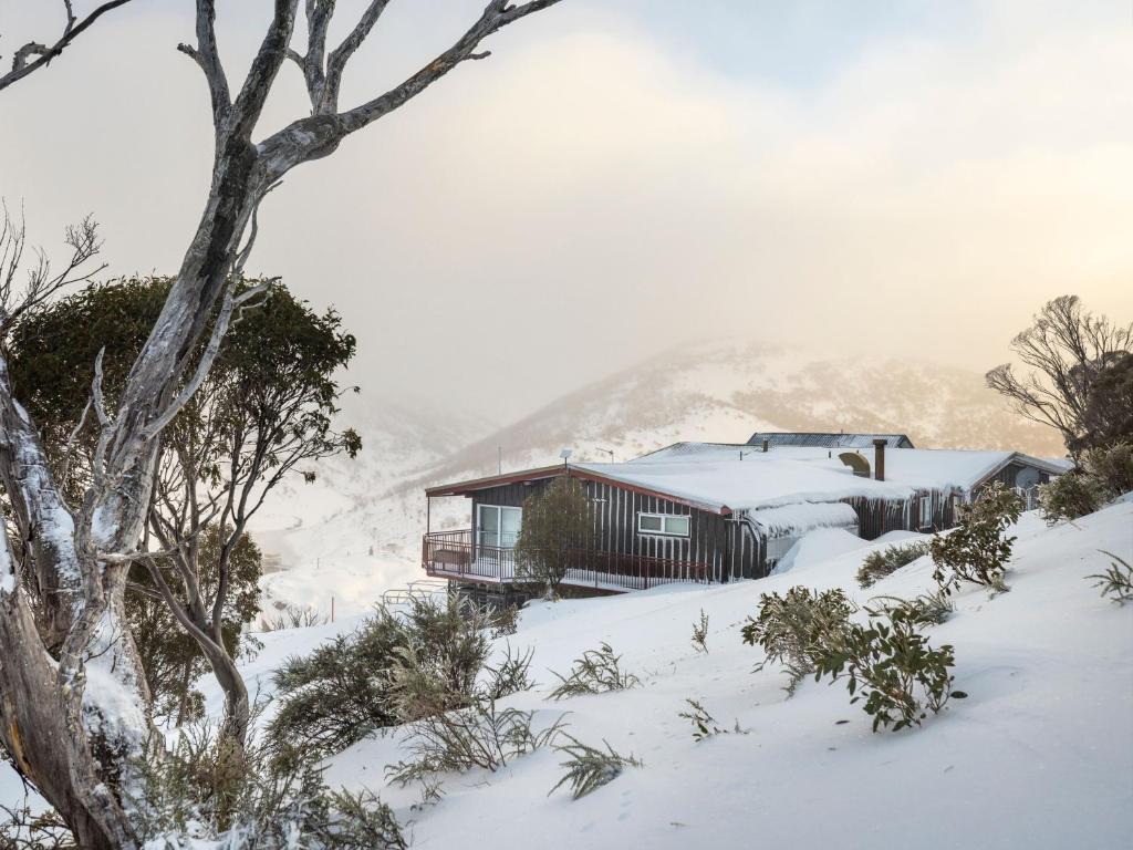 a house in the snow in front of a mountain at Guthega Inn in Perisher Valley