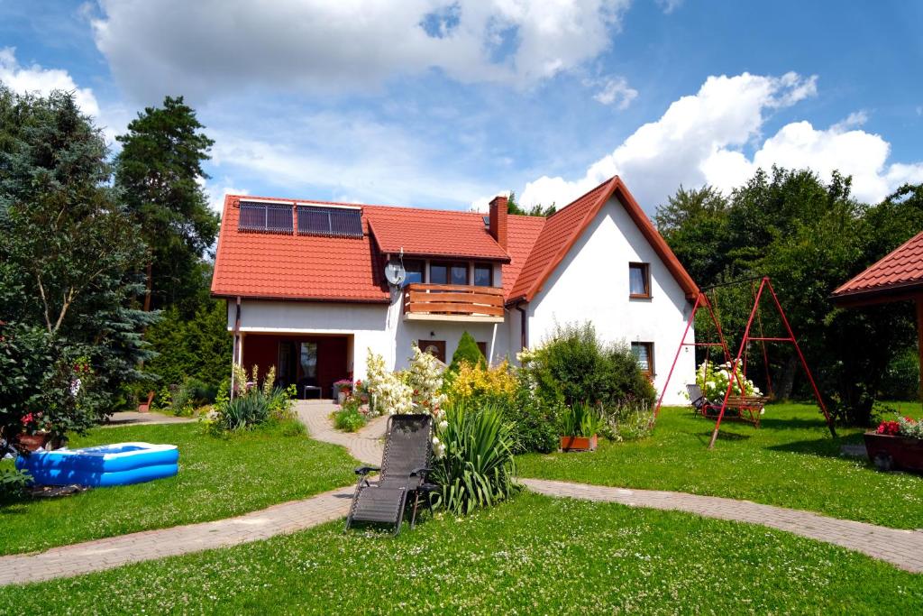 ein Haus mit einem roten Dach und einem Hof in der Unterkunft Gospodarstwo Agroturystyczne Ćmilówka 