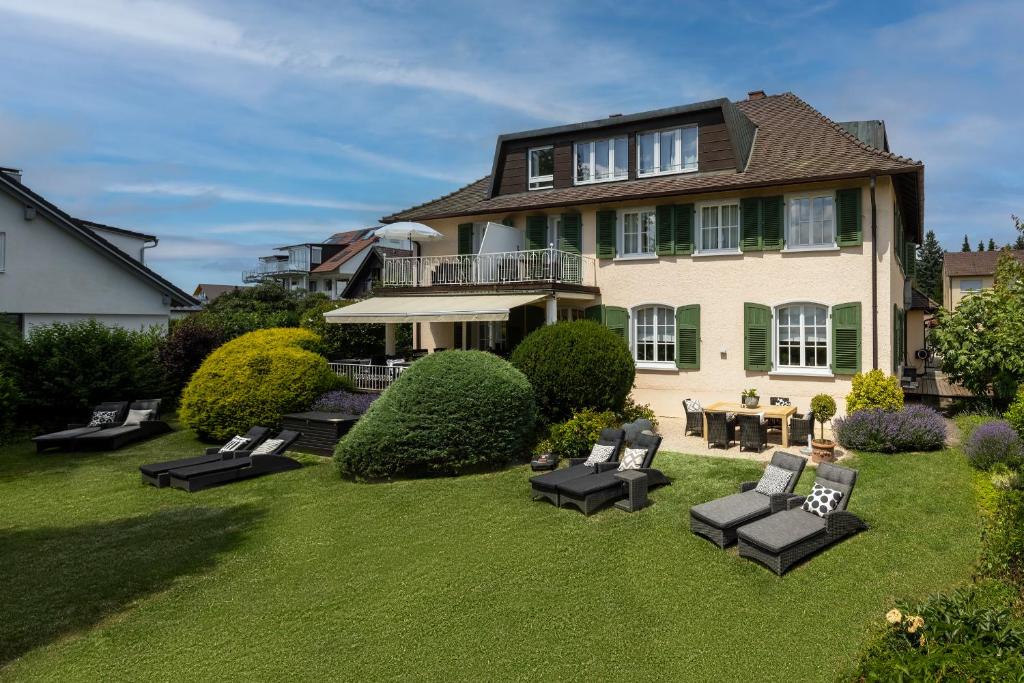 ein großes Haus mit einem Hof mit schwarzen Möbeln in der Unterkunft Villa Neugarten in Hagnau