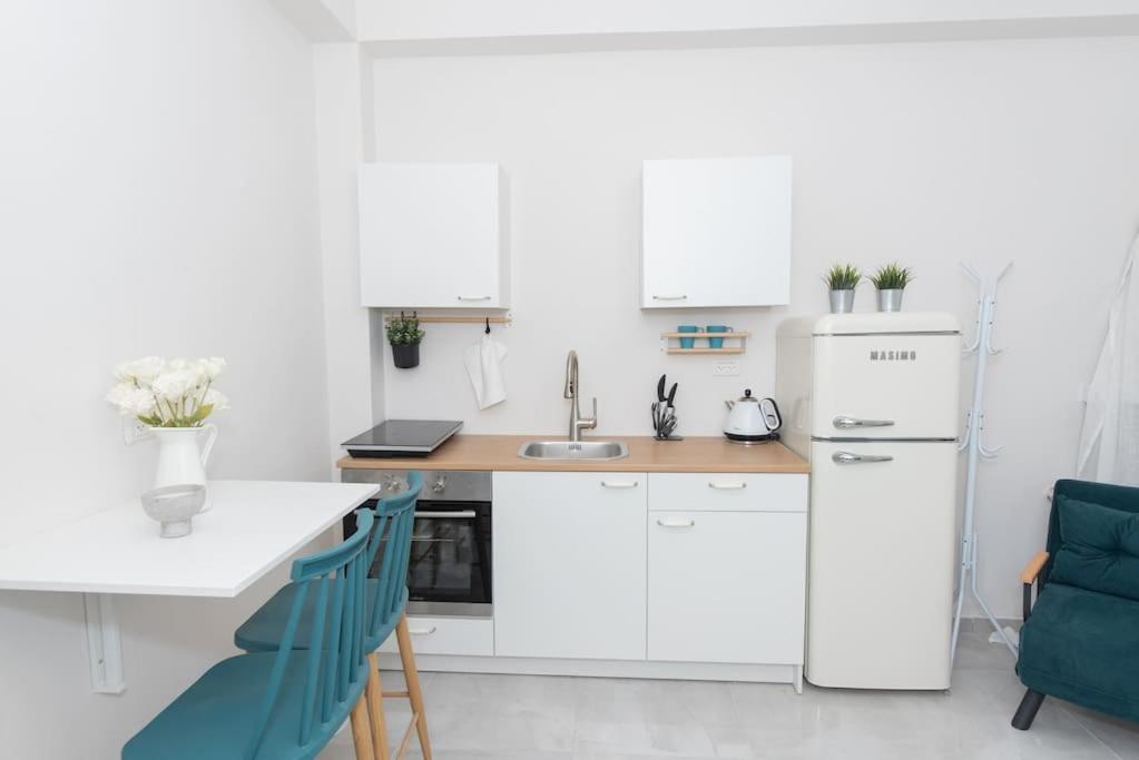 a kitchen with white cabinets and a white refrigerator at Cosy and Suits apartment in Jerusalem