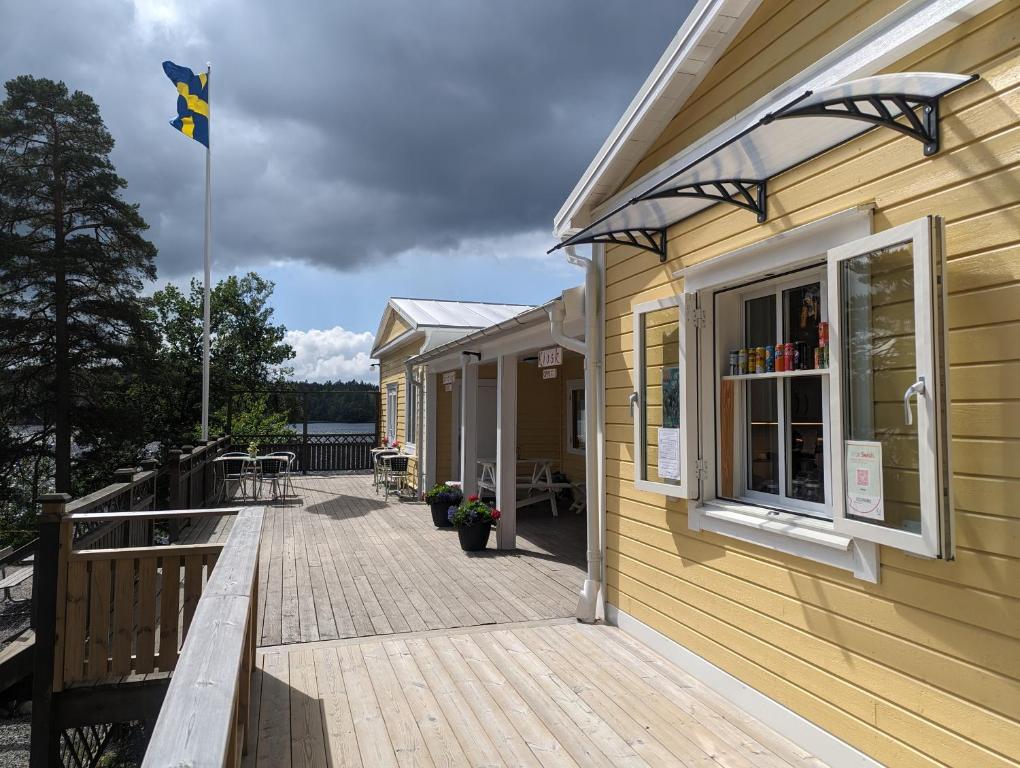 un edificio con una terraza con una bandera. en Vårhaga Vandrarhem, en Sjuntorp