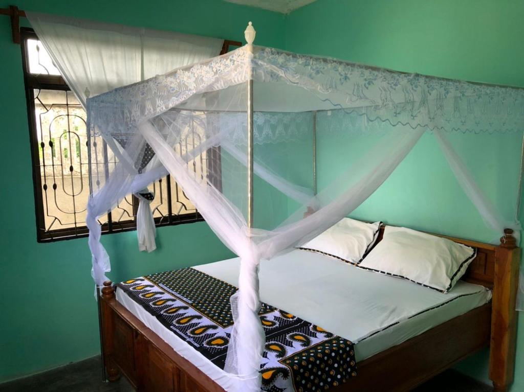 ein Schlafzimmer mit einem Himmelbett und einem Fenster in der Unterkunft BeSwahilid B & B in Bagamoyo