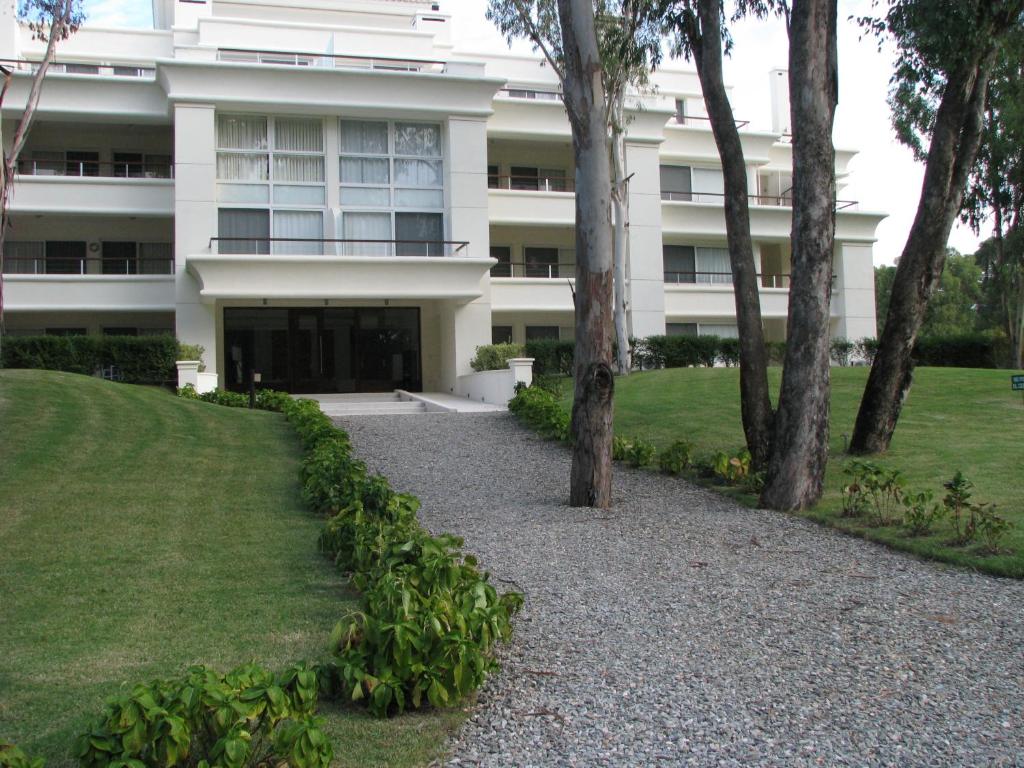 un bâtiment blanc avec des arbres devant lui dans l'établissement Green Park en Punta del Este, à Punta del Este