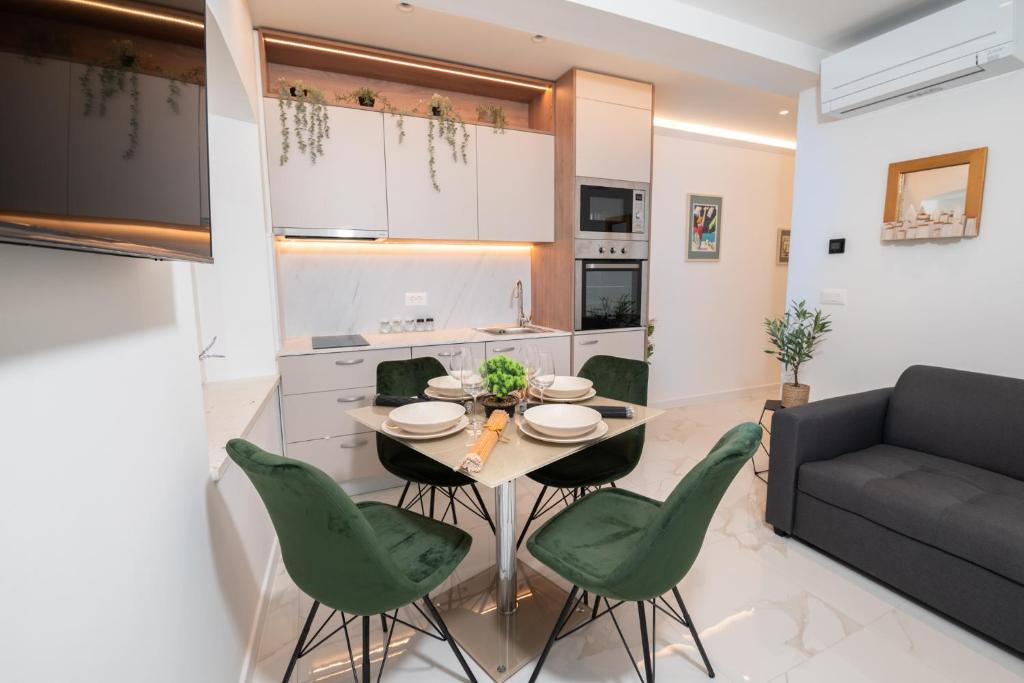 a kitchen and living room with a table and green chairs at Canta Amore Suites in Zadar
