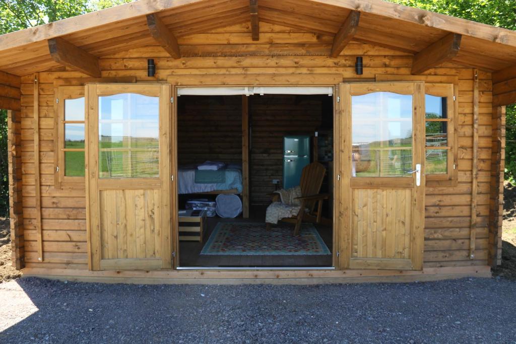a wooden shed with two large sliding doors at Knapp Farm Glamping Lodge 1 in Corscombe