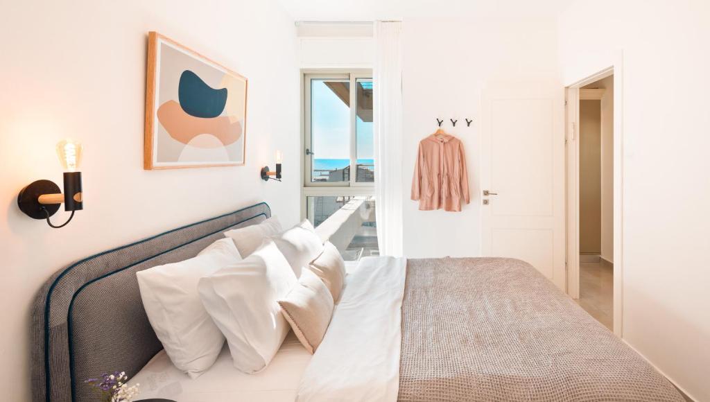 a white bedroom with a bed with white pillows at Mate TLV PORT - By HOMY in Tel Aviv
