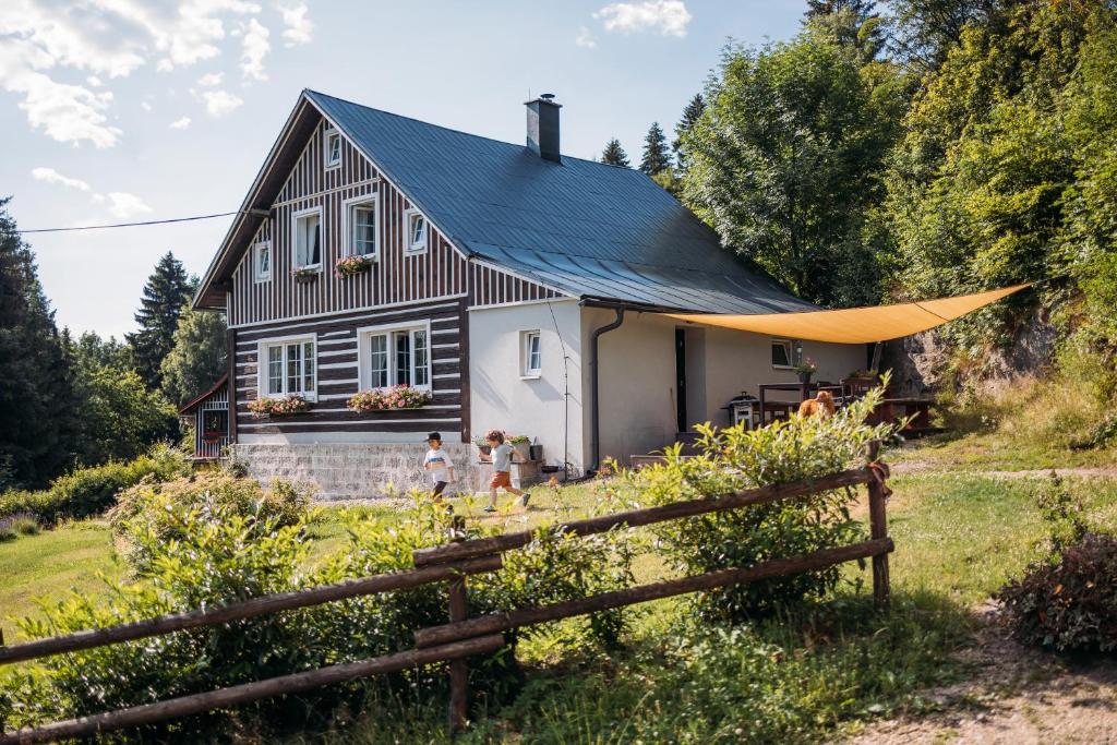 a house with a black roof and a fence at Chata Fajfrtka in Janov nad Nisou