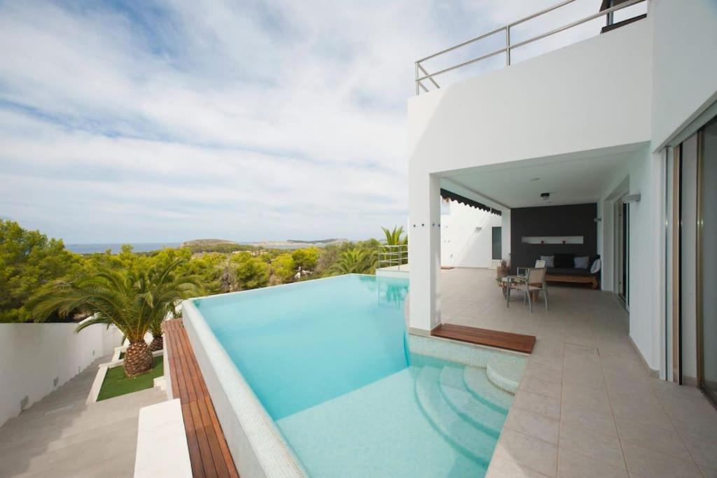een huis met een zwembad op een balkon bij Casa Rosa de los Vientos, al lado de la playa in San Jose de sa Talaia