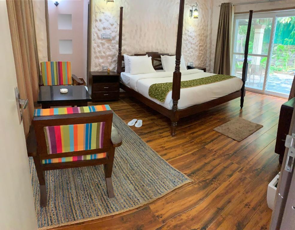 Schlafzimmer mit einem Bett und Holzboden in der Unterkunft Bhil's Kabeela Resort & Spa Kanha in Dhanwār