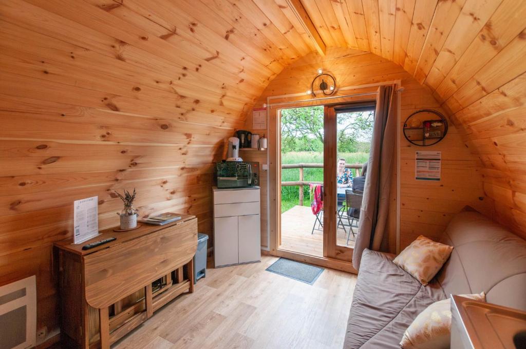 una sala de estar con sofá en una cabaña de madera en Au pré des Alizés - insolite à la ferme des Alizés, en Vallon-sur-Gée