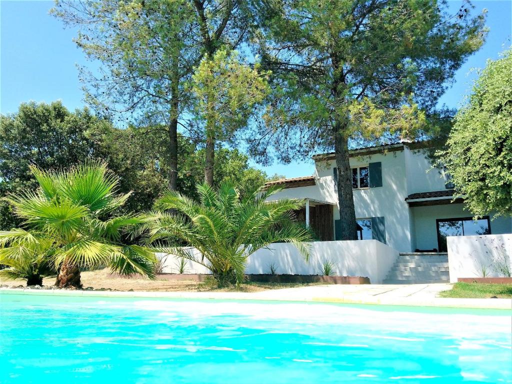 una casa con piscina frente a ella en Villa de 6 chambres avec piscine privee jardin clos et wifi a Saint Bauzille de Montmel, en Saint-Bauzille-de-Montmel