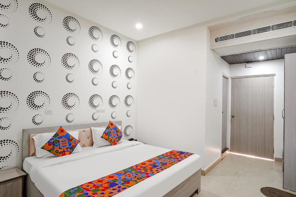 a white bedroom with a bed and a wall with plates at FabHotel Siddhi in Varanasi