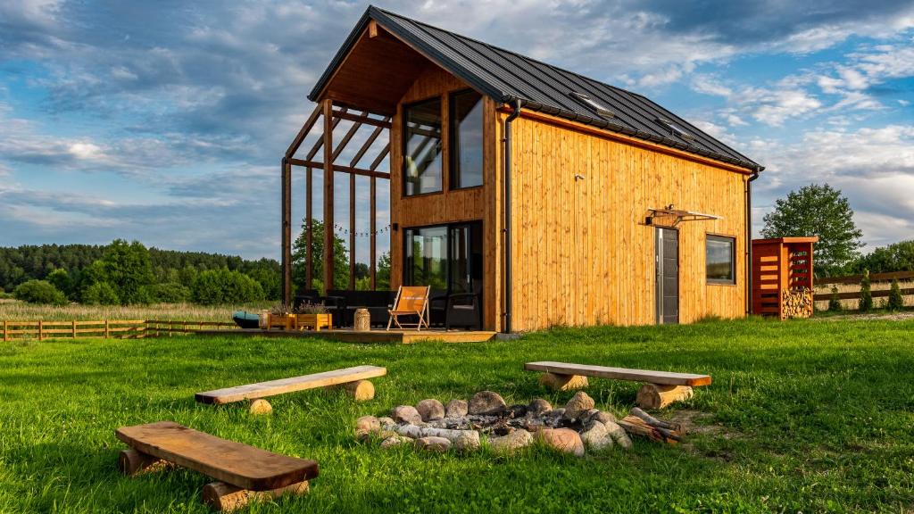 eine kleine Holzhütte in der Mitte eines Feldes in der Unterkunft Apartamenty Sun & Snow Sielska Stodoła z sauną in Trękus