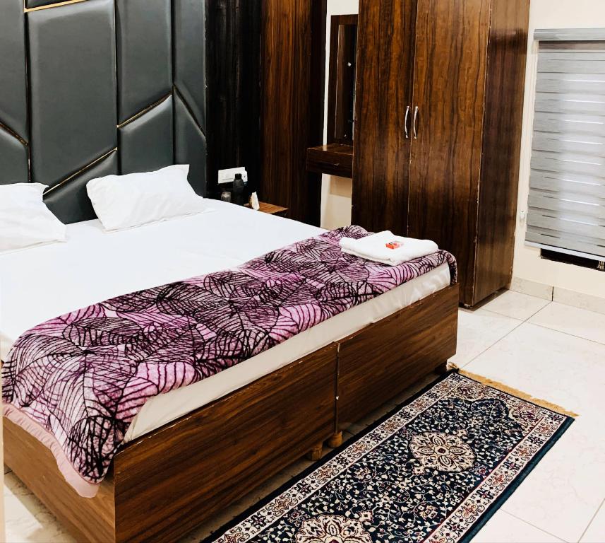 um quarto com uma cama com uma cabeceira em madeira e um tapete em THE R MOTEL Phagwara City -- Full Privacy & Security -- Family,Corporate,Couples Favorite em Phagwāra