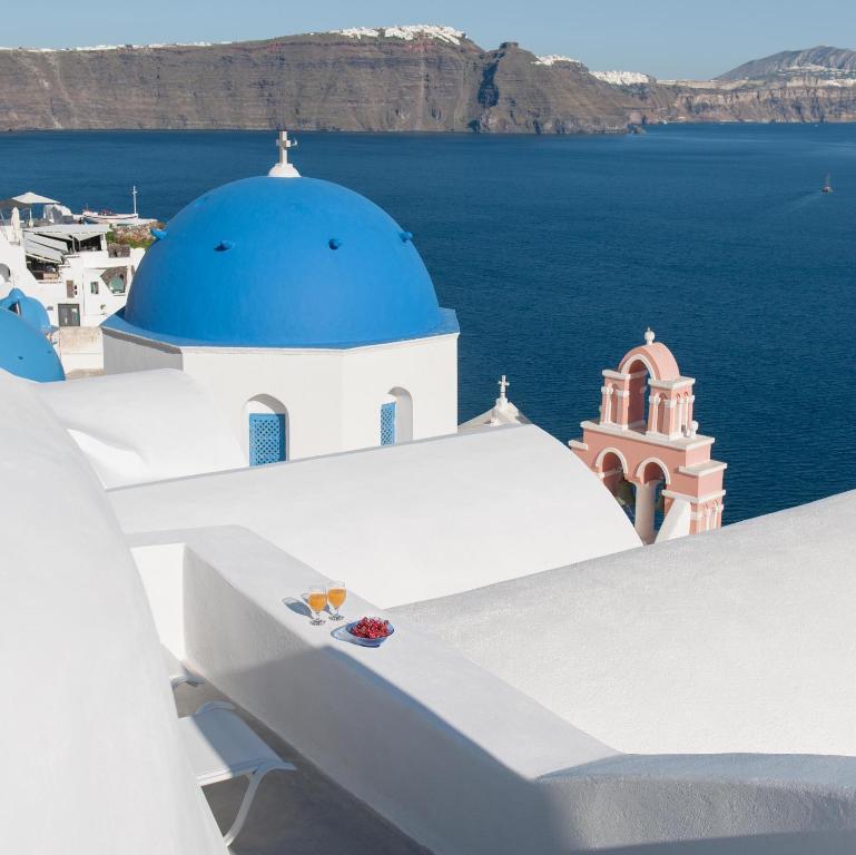 a view of a blue domed building and the ocean at Evmenia Luxury Cave Villa in Oia