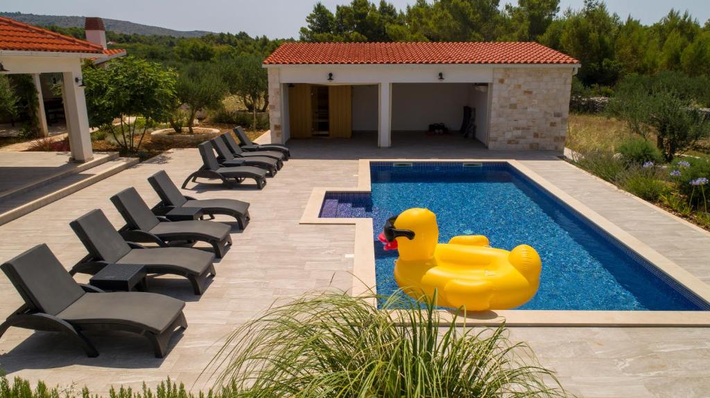 a yellow rubber duck in a swimming pool with chairs at Luxury Villa Nature with heated private pool, sauna & fire pit, a short walk to the beach in Milna