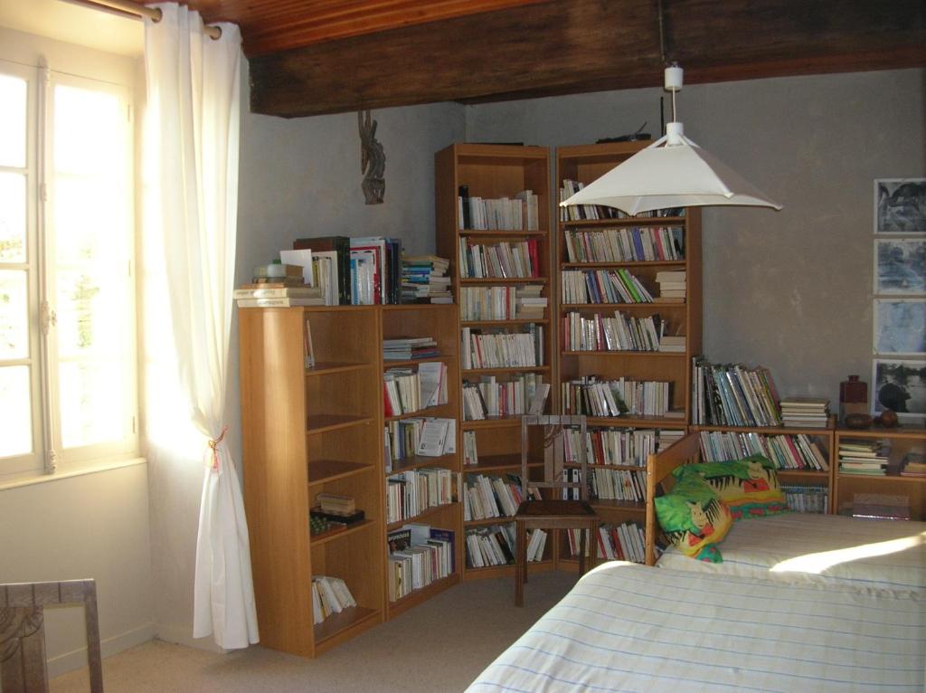 una camera da letto con librerie piene di libri di B&B "Les Remparts" a Vouvant