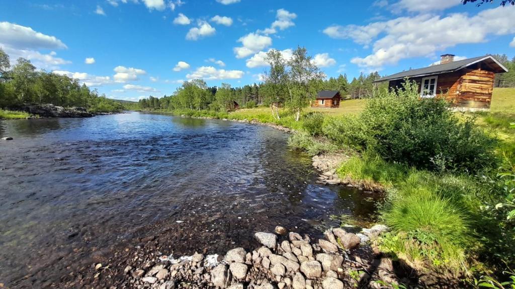 einem Fluss vor einem Blockhaus in der Unterkunft Leppälän vanhatupa rantasaunalla in Utsjoki