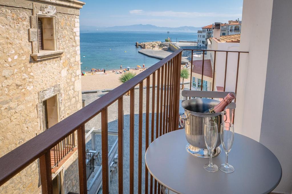 uma mesa com um balde numa varanda com vista para o oceano em Taverna de la Sal Boutique Hotel em L'Escala