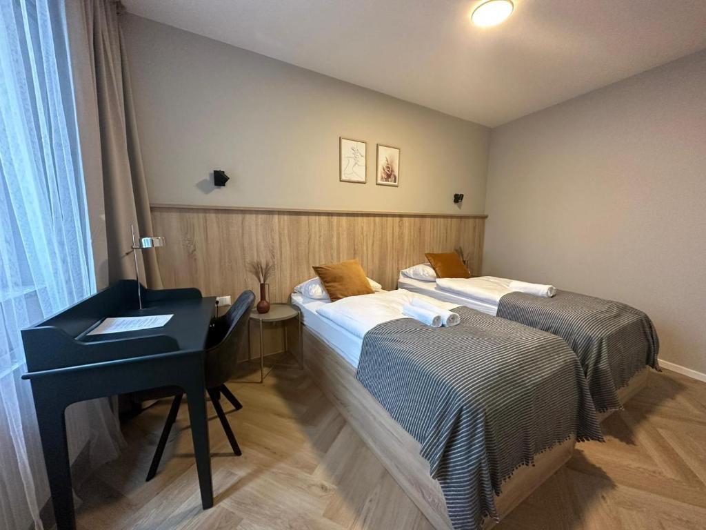 a room with two beds and a desk in it at Aparthotel Lenau in Hannover