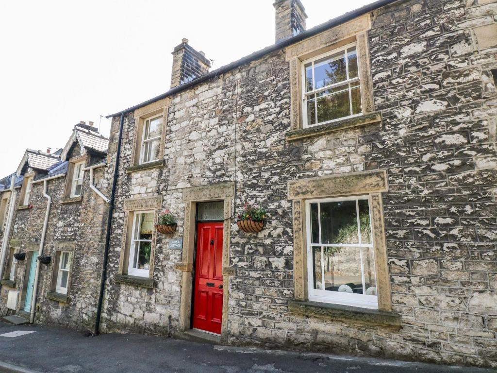 a stone building with a red door and windows at Knoll Cottage in Bakewell