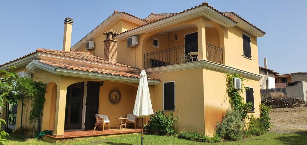 una casa gialla con ombrellone e patio di Artemisia bed and breakfast a SantʼAnna Arresi