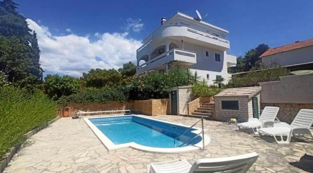 a house with a swimming pool in front of a house at Villa West Point in Okrug Donji