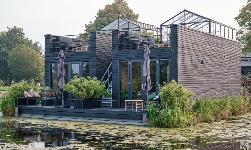 a wooden house with a roof over a body of water at GreenFloat Boskoop #2 Mica & Luca in Boskoop