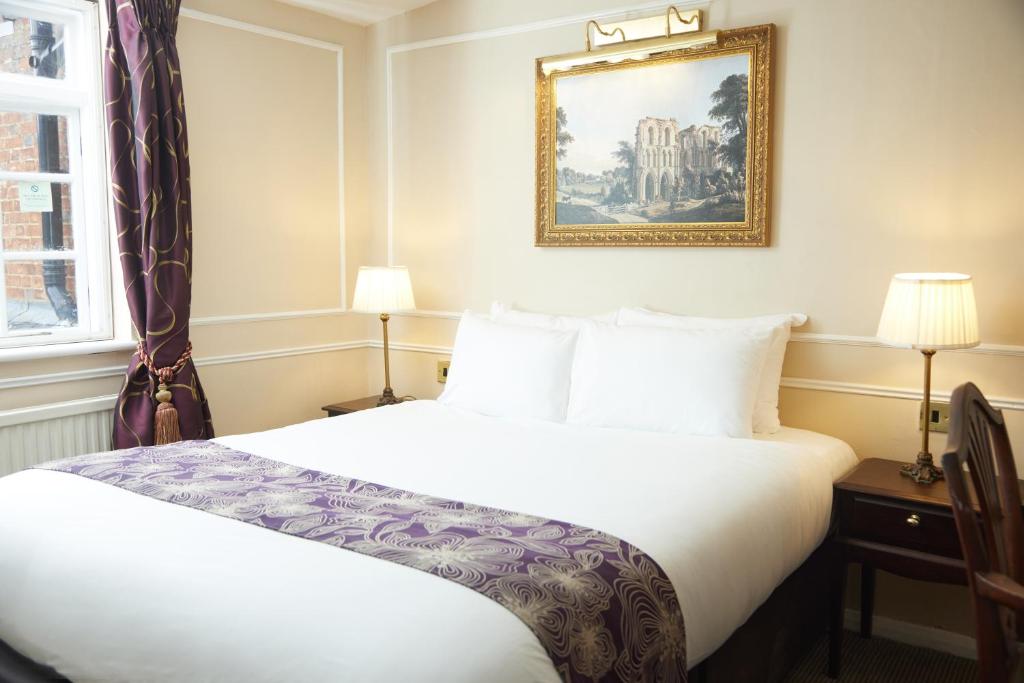 um quarto de hotel com uma cama e uma fotografia na parede em Cock Hotel by Greene King Inns em Stony Stratford