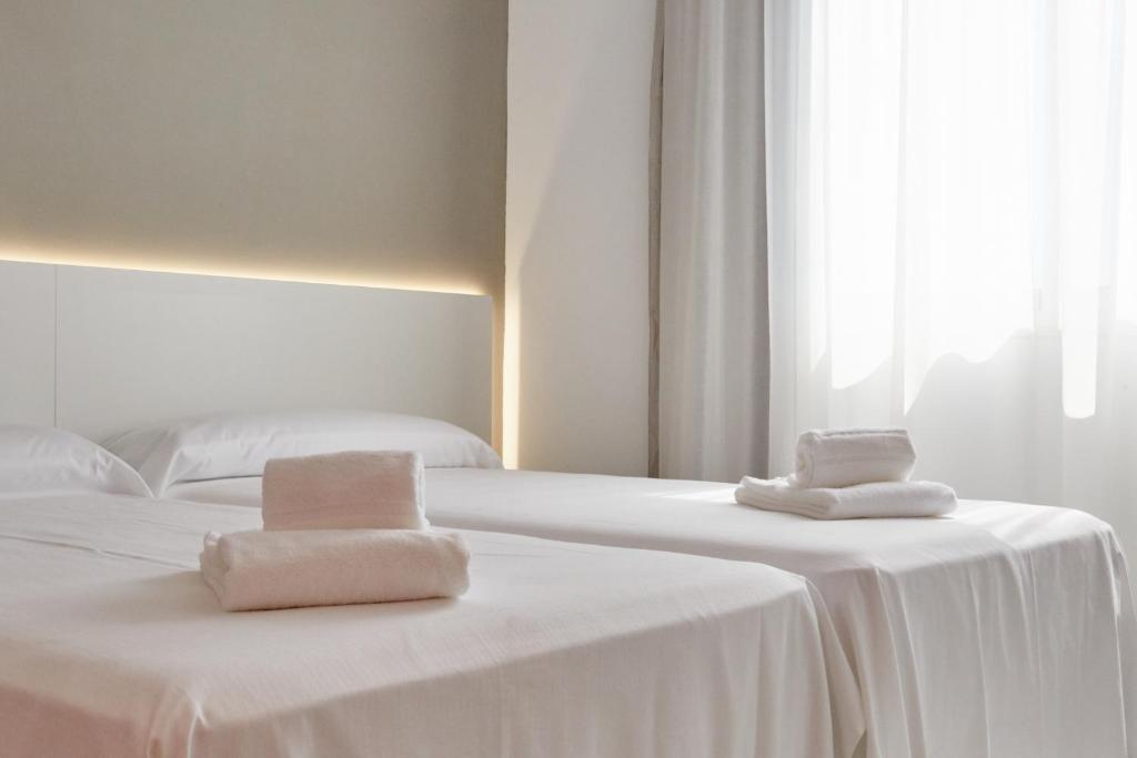 2 camas blancas con toallas en una habitación en Hotel DL Port, en Castellón de la Plana