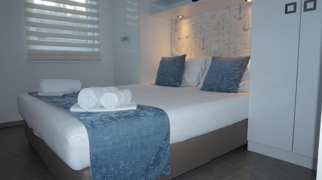 um quarto com uma grande cama branca com almofadas azuis em Mandy Apartman em Baska