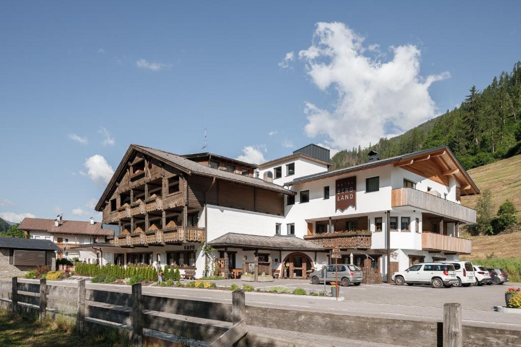 a large building with cars parked in a parking lot at Hotel Bergland in Cadipietra