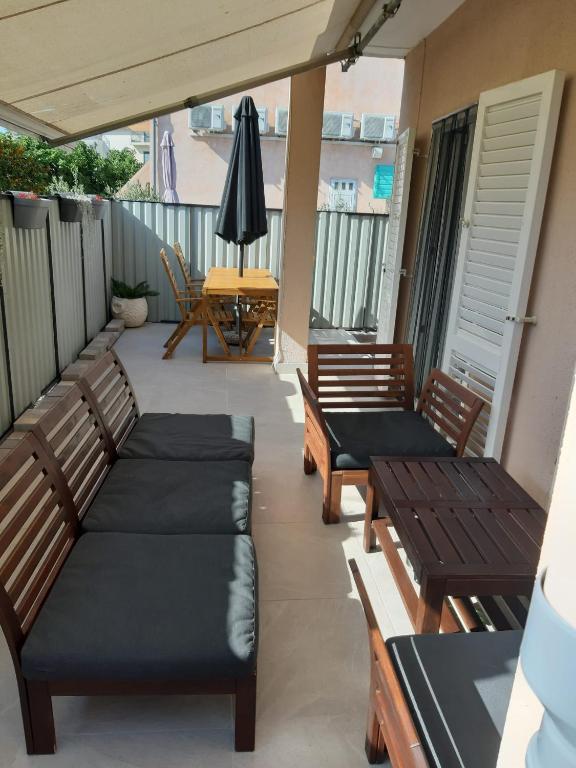 a balcony with benches and a table with an umbrella at Kuća za odmor Emanuela in Vodice