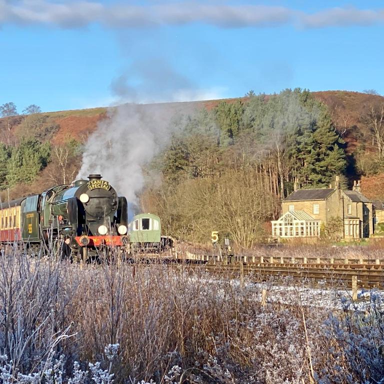 a steam train is coming down the tracks at Grove House Levisham in Pickering