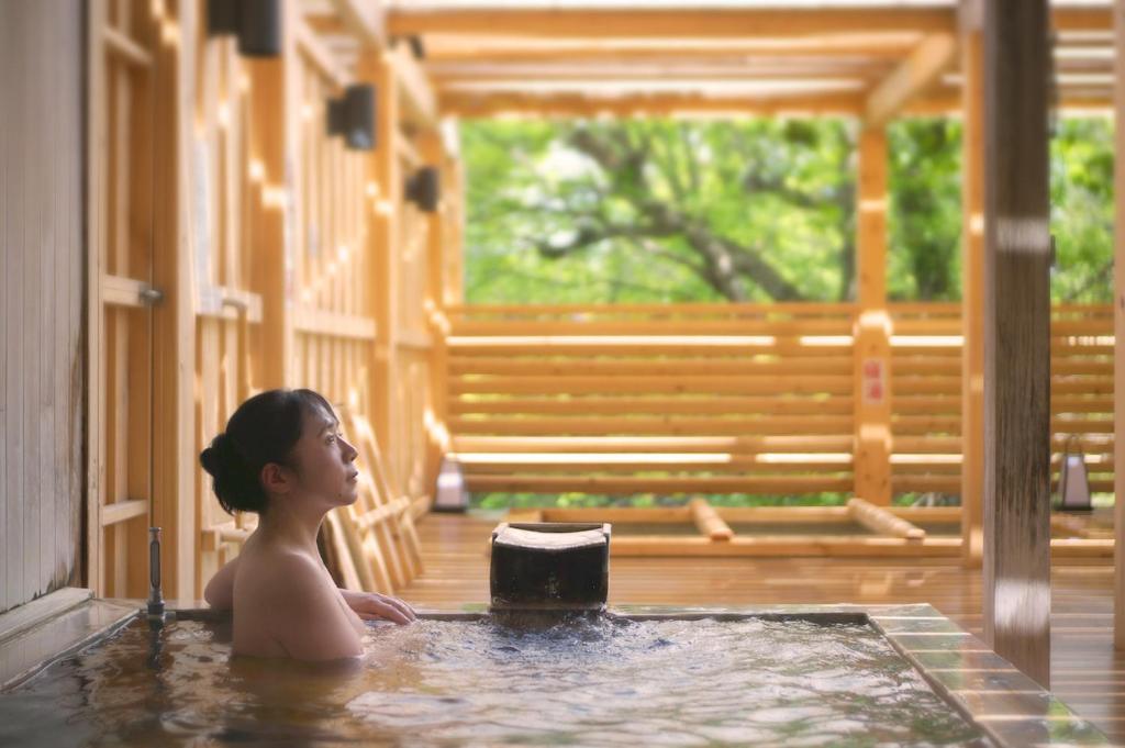 a woman sitting in a hot tub in a house at Itsukushien 