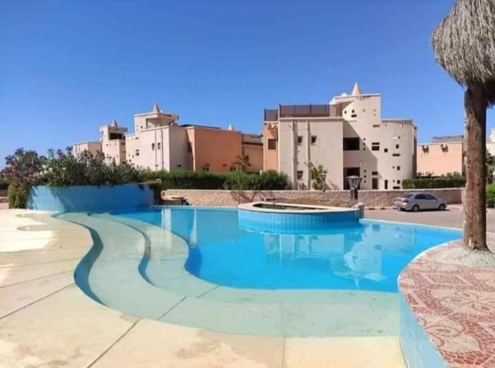 uma piscina num resort com edifícios ao fundo em شاليه ديمورا عائلات فقط Dimora Chalet Only Family em Dawwār Muḩammad Abū Shunaynah