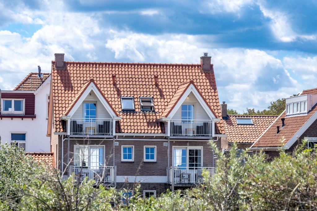 une grande maison avec un toit rouge dans l'établissement Bed & Breakfast Huys aan zee, à Domburg