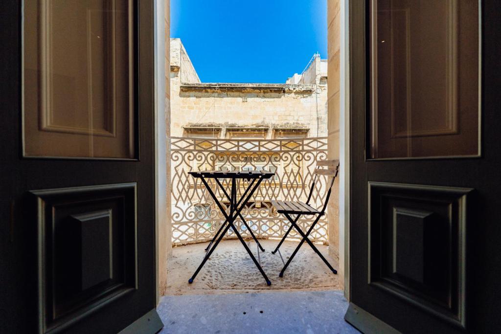 una porta aperta con un tavolo e una sedia su un balcone di Valletta Collection - Republica Suites a La Valletta