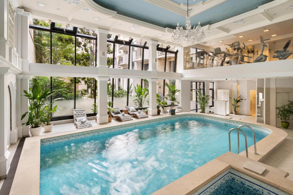 a pool in a house with a large room with windows at Queen's Court Hotel & Residence in Budapest