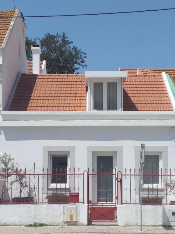 a white house with a red fence in front of it at Casa do Lado - The next door in Seixal